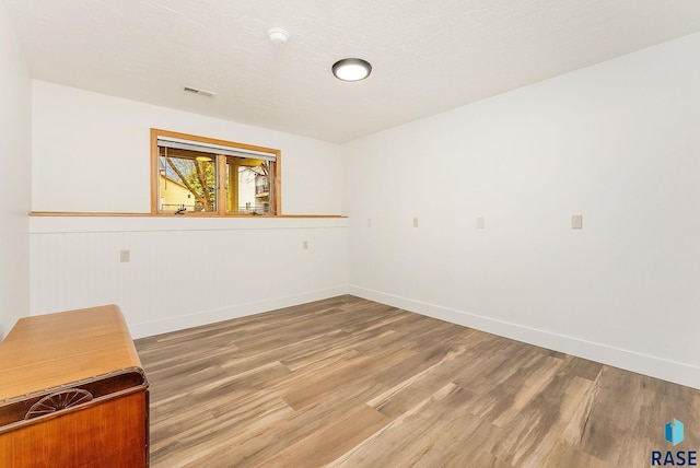 empty room featuring light wood-type flooring, baseboards, and visible vents