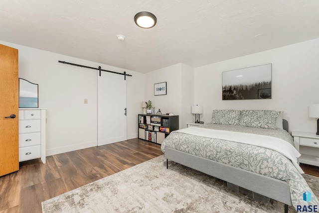 bedroom featuring baseboards, a barn door, and wood finished floors