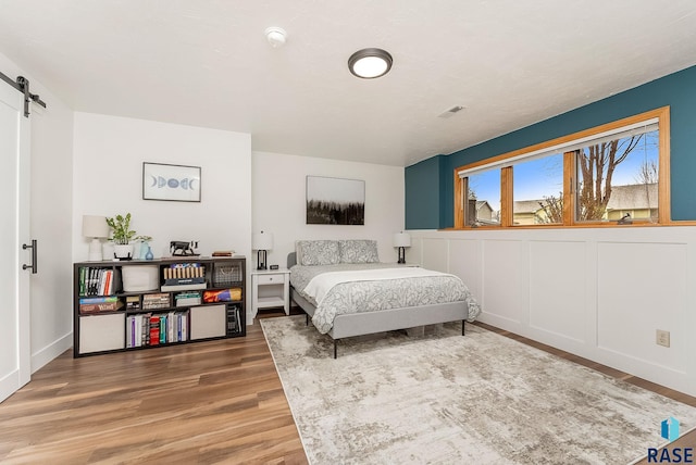 bedroom featuring a barn door, visible vents, and wood finished floors