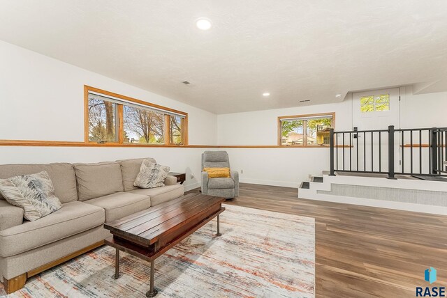 living room featuring stairs, wood finished floors, baseboards, and recessed lighting