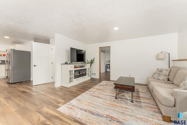living area with recessed lighting, baseboards, visible vents, wood finished floors, and a fireplace
