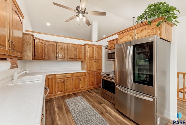 kitchen with a ceiling fan, stainless steel appliances, a sink, wood finished floors, and light countertops