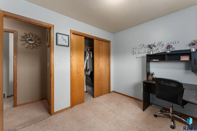 carpeted office with a textured ceiling and baseboards