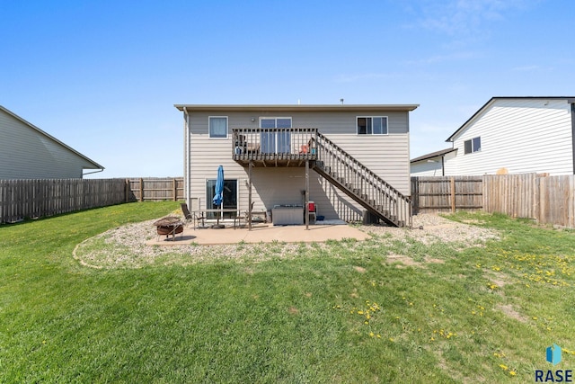 rear view of house with a lawn, stairs, a deck, a fire pit, and a fenced backyard