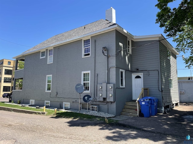 207 W 14th St, Sioux Falls, SD 57104 - back of property with a chimney, stucco siding, and a shingled roof