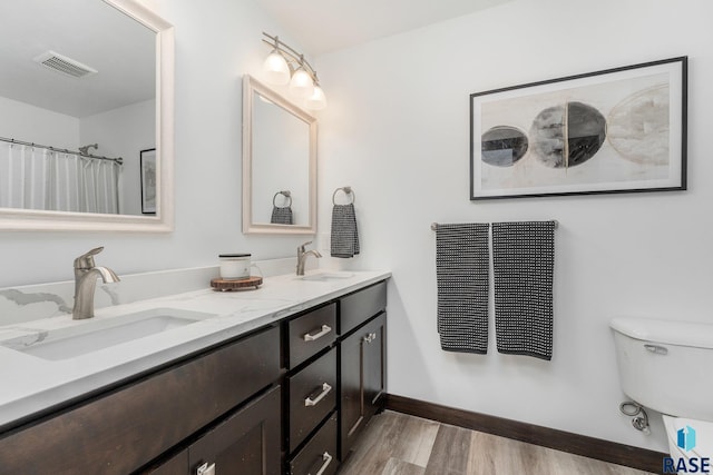 bathroom with visible vents, wood finished floors, baseboards, and a sink
