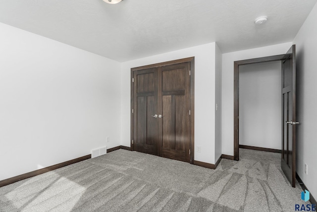 unfurnished bedroom with light colored carpet, baseboards, a closet, and visible vents