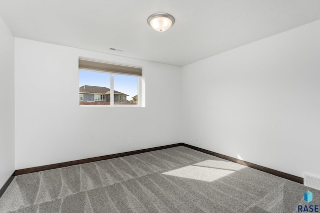 empty room with carpet, visible vents, and baseboards
