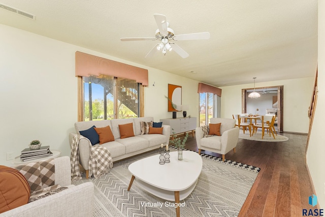 living area with a textured ceiling, visible vents, a ceiling fan, and hardwood / wood-style flooring