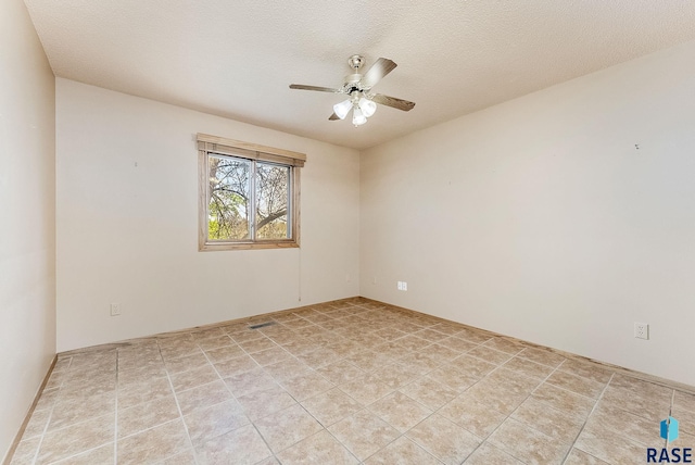 unfurnished room with a ceiling fan, visible vents, and a textured ceiling