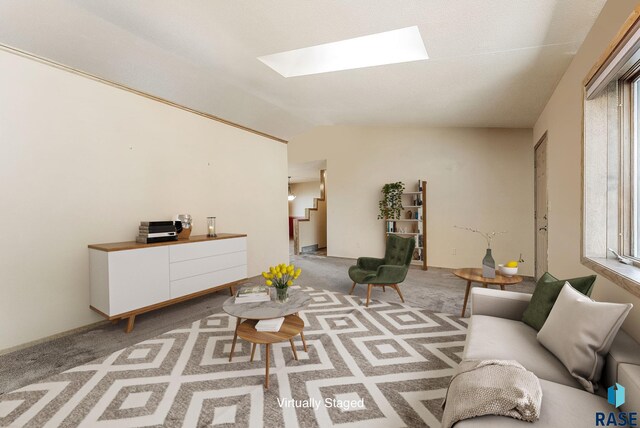 carpeted living area featuring stairway and vaulted ceiling with skylight