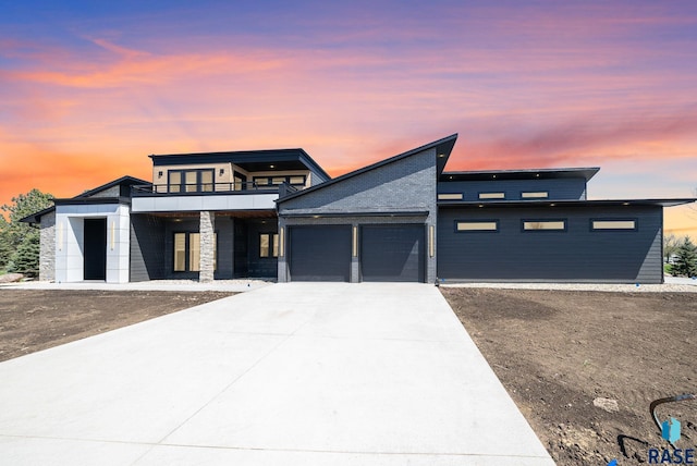 prairie-style house with concrete driveway, a garage, and a balcony