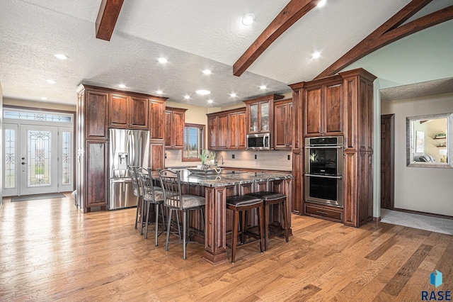 6601 Lenola Hts, Wentworth, SD 57075 - kitchen with a center island with sink, light wood finished floors, appliances with stainless steel finishes, and a kitchen bar
