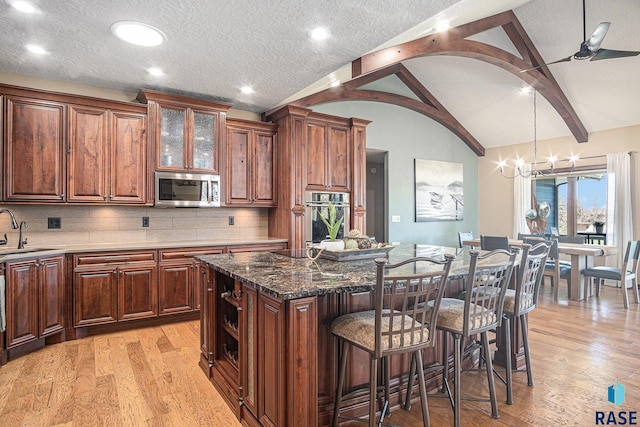 6601 Lenola Hts, Wentworth, SD 57075 - kitchen with stainless steel appliances, lofted ceiling with beams, a breakfast bar area, light wood-style flooring, and a center island