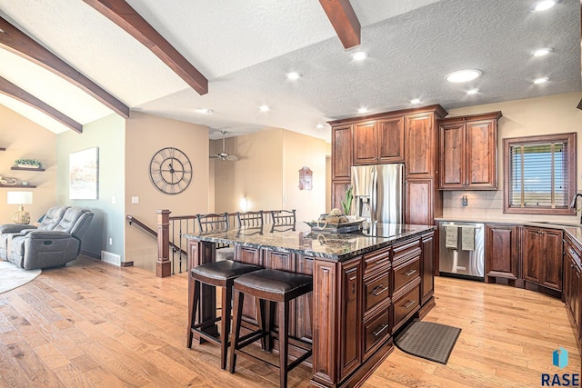 6601 Lenola Hts, Wentworth, SD 57075 - kitchen featuring a breakfast bar, dark stone counters, open floor plan, vaulted ceiling with beams, and appliances with stainless steel finishes