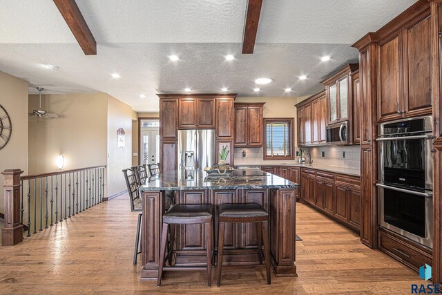 6601 Lenola Hts, Wentworth, SD 57075 - kitchen featuring a breakfast bar, light wood finished floors, appliances with stainless steel finishes, and a textured ceiling