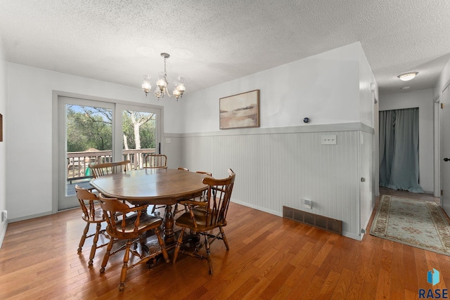 20395 Northgrove Loop, Brookings, SD 57006 - dining space with a textured ceiling, wood finished floors, wainscoting, and a notable chandelier