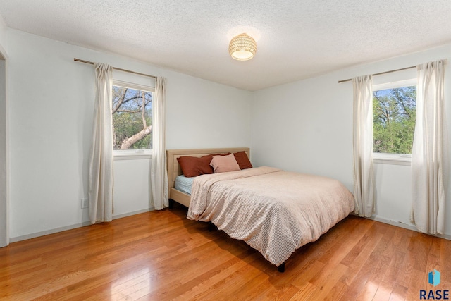 20395 Northgrove Loop, Brookings, SD 57006 - bedroom with multiple windows, light wood-style floors, and a textured ceiling
