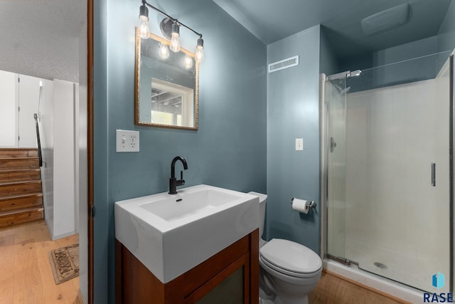 20395 Northgrove Loop, Brookings, SD 57006 - full bathroom featuring toilet, wood finished floors, visible vents, a shower stall, and vanity