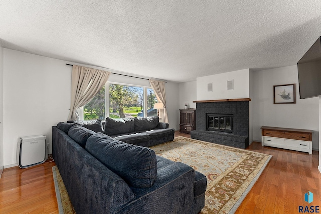 20395 Northgrove Loop, Brookings, SD 57006 - living room featuring a textured ceiling, a brick fireplace, visible vents, and wood finished floors