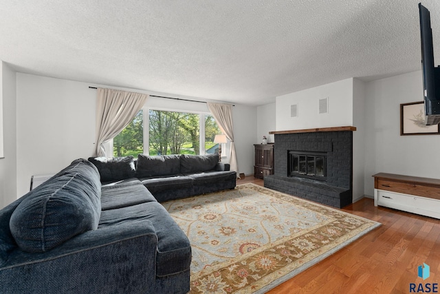20395 Northgrove Loop, Brookings, SD 57006 - living room featuring a brick fireplace, visible vents, a textured ceiling, and wood finished floors