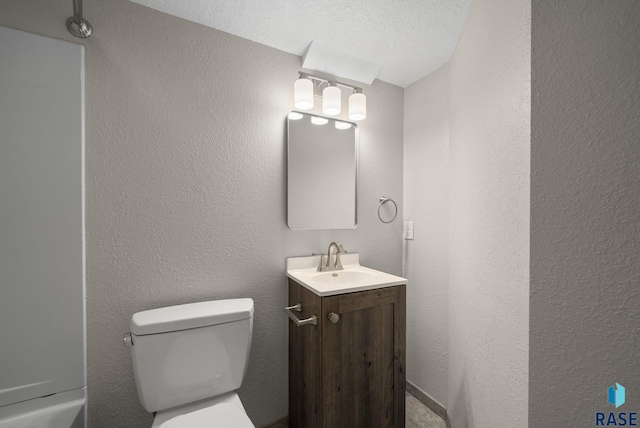 bathroom featuring toilet, vanity, and a textured wall