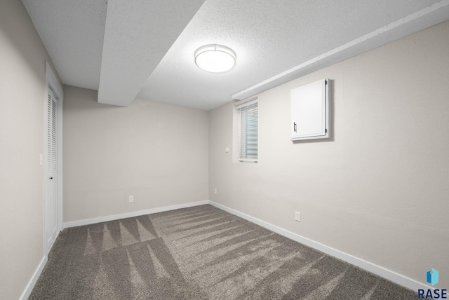 basement featuring baseboards, carpet flooring, and a textured ceiling