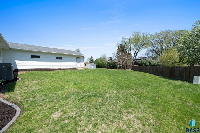 view of yard featuring central AC unit, fence, an outbuilding, and a storage unit