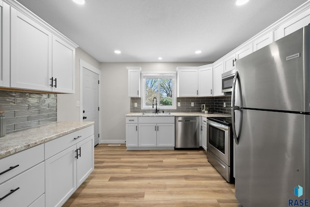 kitchen featuring a sink, stainless steel appliances, recessed lighting, white cabinetry, and decorative backsplash
