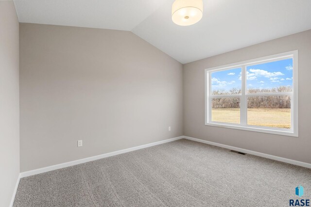 empty room featuring visible vents, baseboards, lofted ceiling, and carpet floors