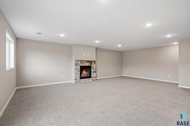 unfurnished living room with carpet, baseboards, a fireplace, and recessed lighting