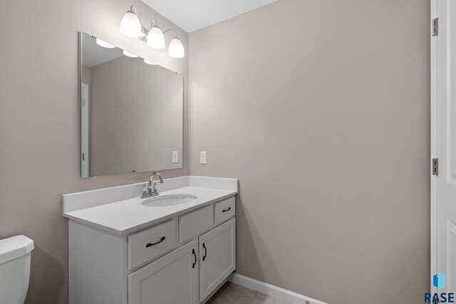 bathroom featuring toilet, baseboards, and vanity