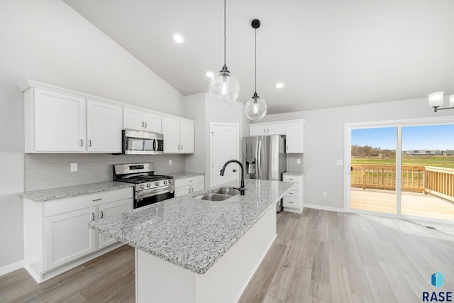 kitchen featuring light wood finished floors, appliances with stainless steel finishes, vaulted ceiling, and a sink