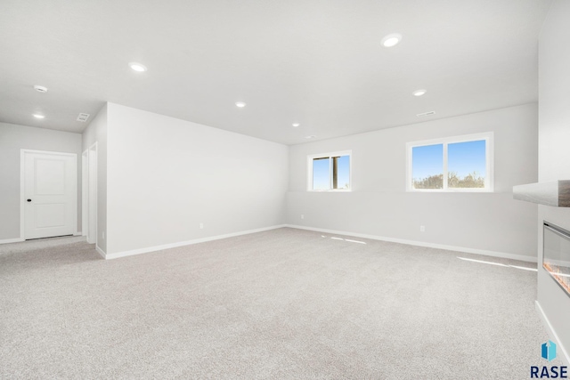 spare room with baseboards, recessed lighting, and light colored carpet