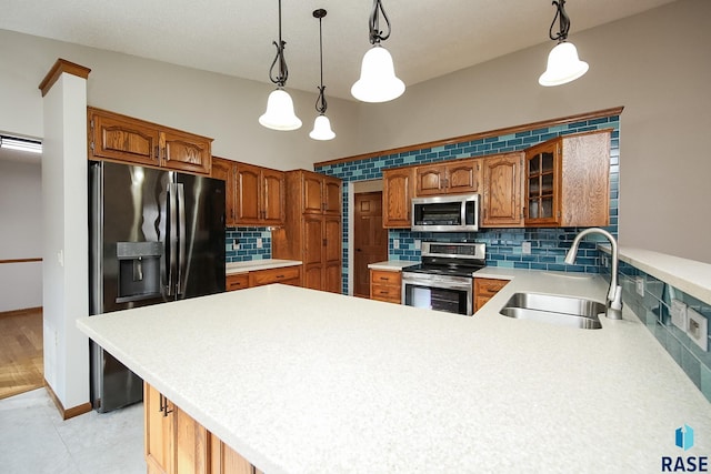 kitchen featuring a peninsula, a sink, stainless steel appliances, light countertops, and decorative backsplash