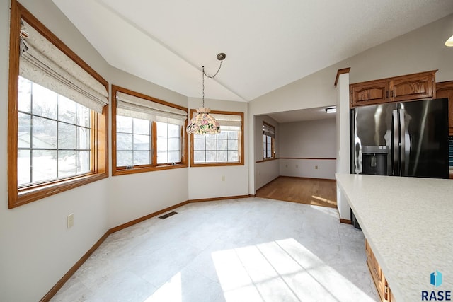 kitchen featuring stainless steel fridge with ice dispenser, baseboards, decorative light fixtures, light countertops, and vaulted ceiling