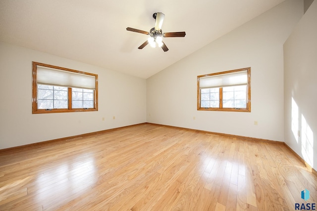 spare room with baseboards, light wood-style flooring, plenty of natural light, and vaulted ceiling