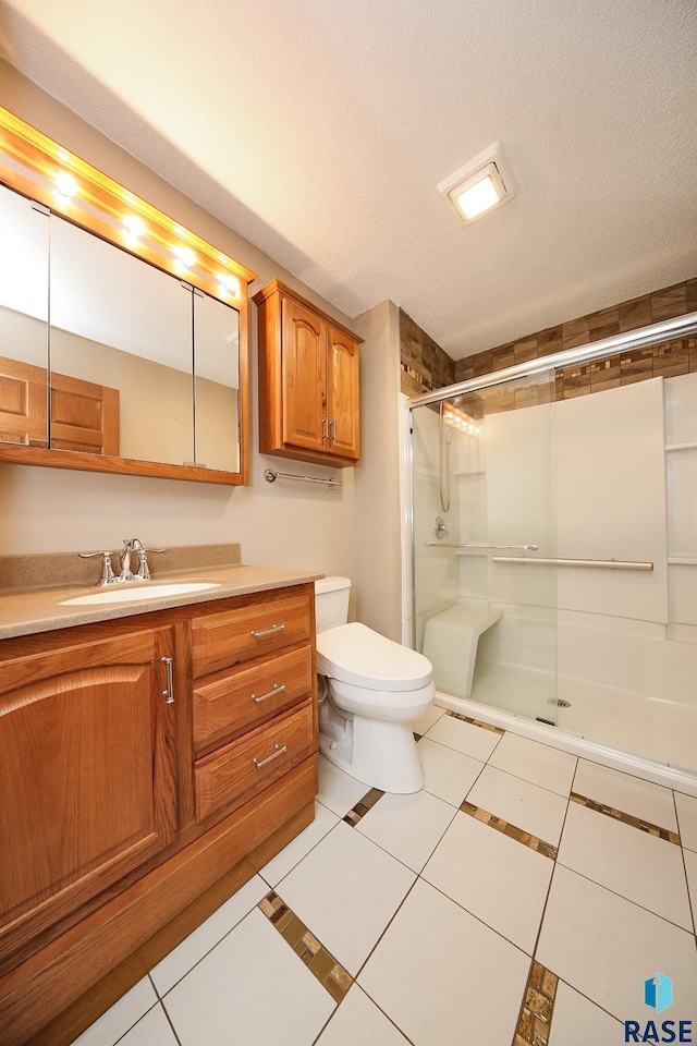 bathroom with a textured ceiling, toilet, a shower stall, tile patterned floors, and vanity