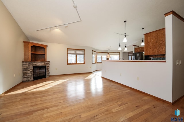 unfurnished living room with rail lighting, light wood-style floors, a fireplace, and baseboards