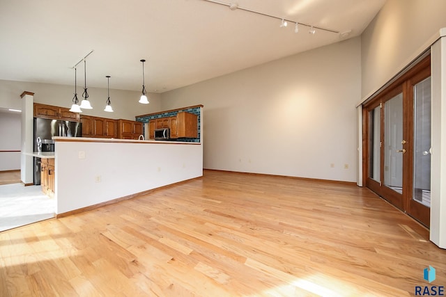 unfurnished living room with rail lighting and light wood-style floors