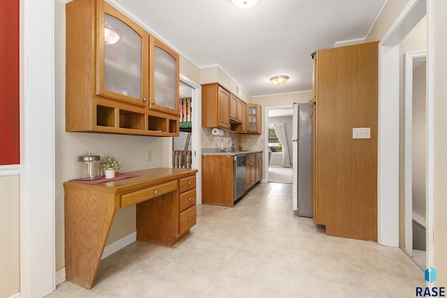 kitchen featuring glass insert cabinets, brown cabinetry, a sink, light countertops, and appliances with stainless steel finishes