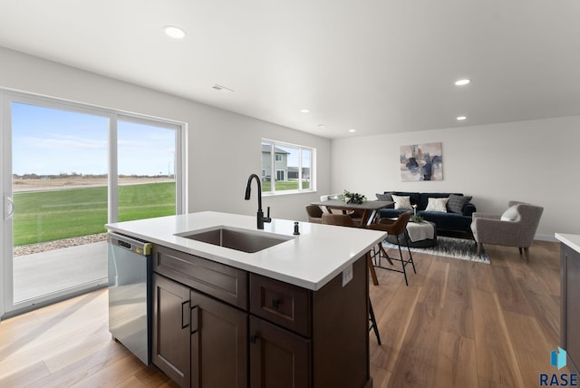 kitchen featuring recessed lighting, dishwasher, a sink, light countertops, and light wood-type flooring