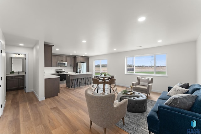living room with light wood finished floors, baseboards, and recessed lighting