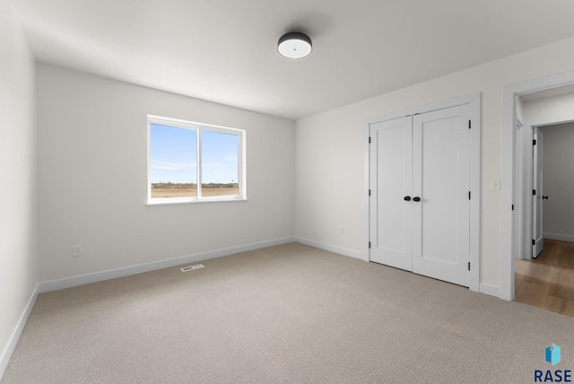 unfurnished bedroom featuring baseboards, a closet, visible vents, and carpet