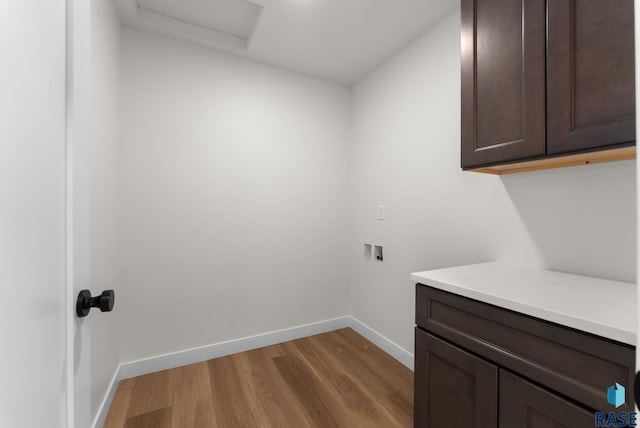clothes washing area featuring wood finished floors, cabinet space, attic access, hookup for a washing machine, and baseboards