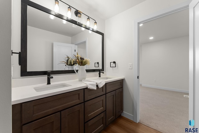bathroom featuring a sink, double vanity, baseboards, and recessed lighting