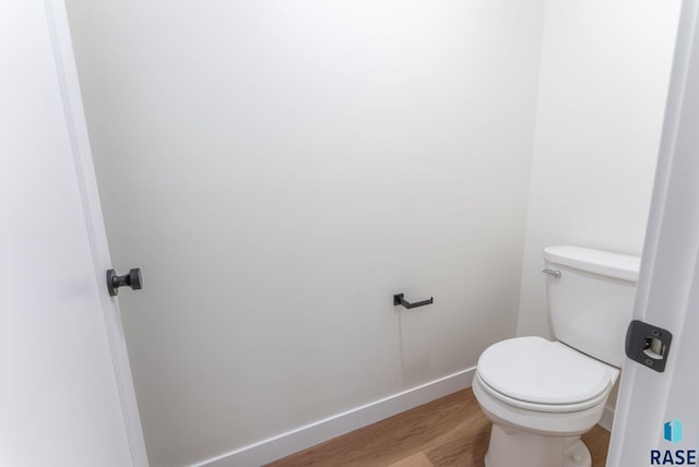 bathroom with toilet, baseboards, and wood finished floors