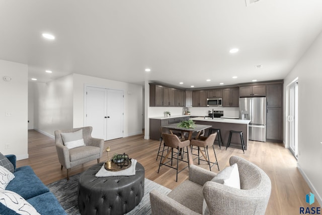 living area with baseboards, recessed lighting, and light wood-type flooring
