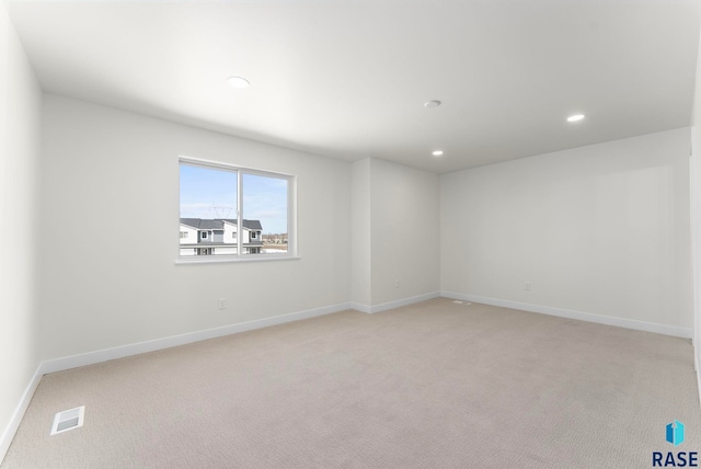 spare room with light colored carpet, baseboards, visible vents, and recessed lighting