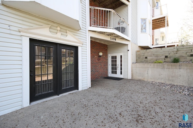 entrance to property featuring french doors, a balcony, and fence